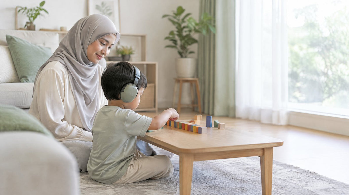 A mother sitting calmly beside her young son as he lines up wooden blocks at home