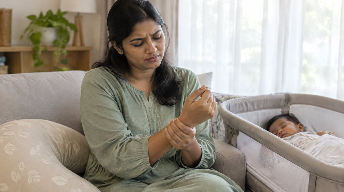 A new mother holding her sore wrist while her baby sleeps beside her