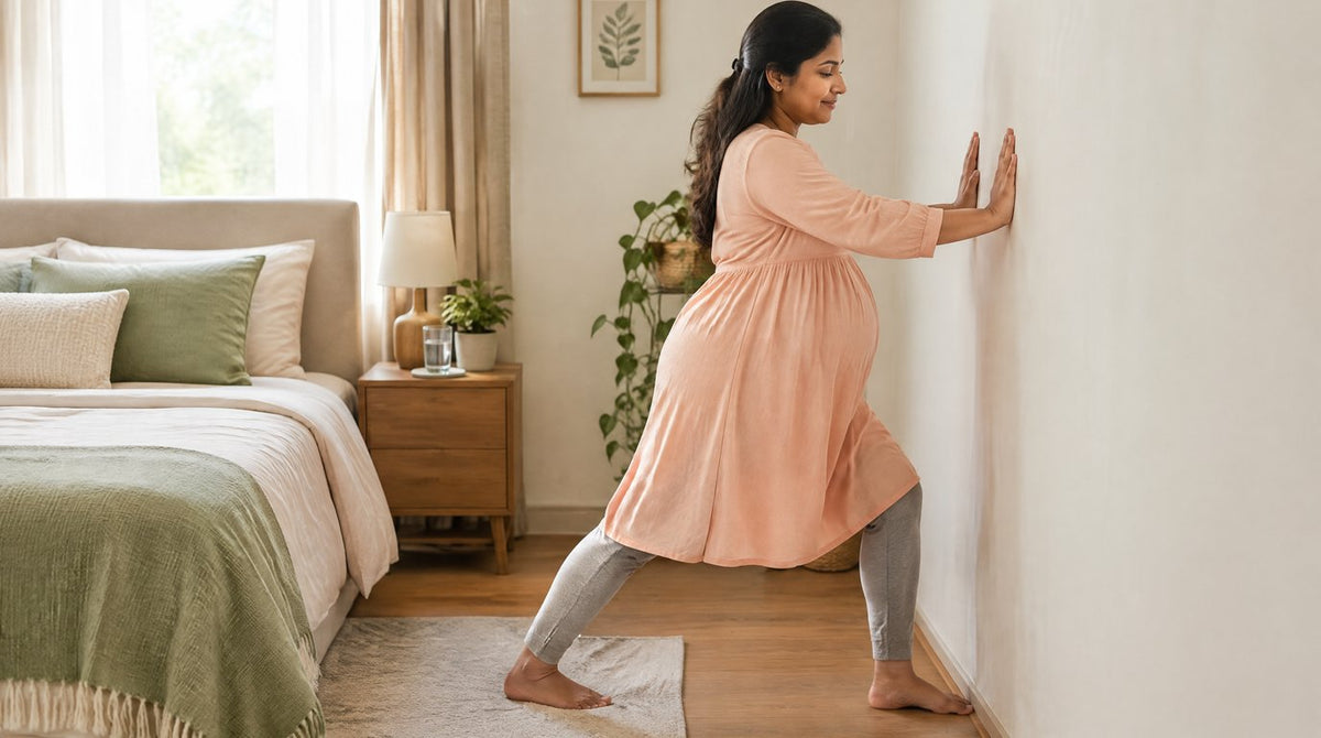 A pregnant woman doing a gentle calf stretch against a bedroom wall