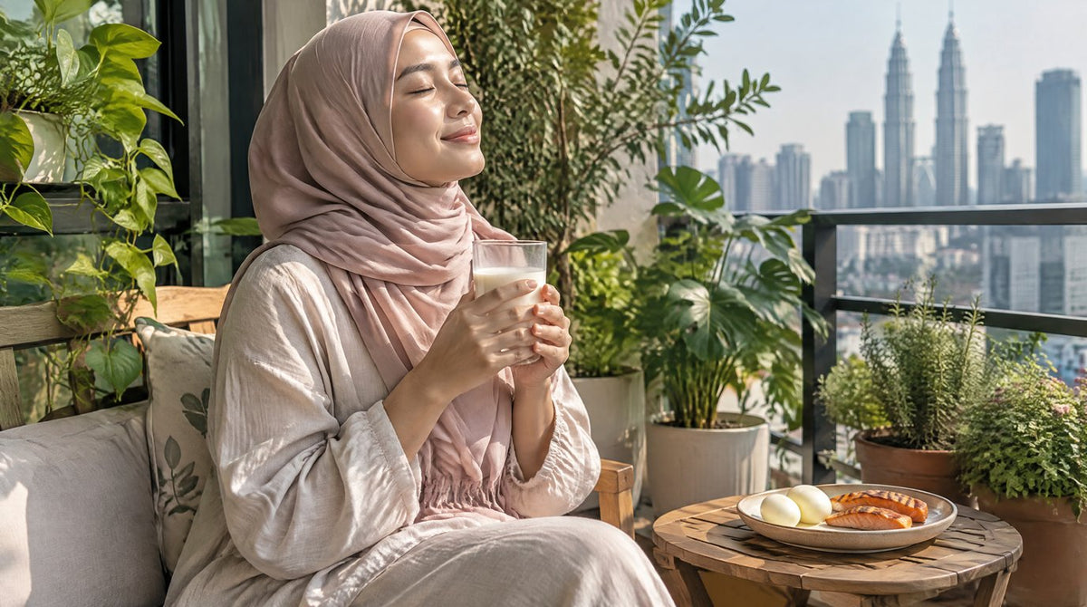 A woman in a hijab sitting in morning sunlight on a balcony with a glass of milk