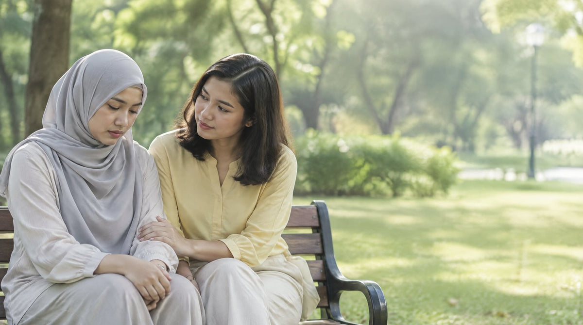 Two friends sitting on a park bench, one listening supportively to the other