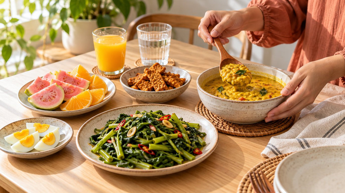 Home-cooked Malaysian lunch with stir-fried kangkung, dhal curry, tempeh, boiled eggs, guava and orange