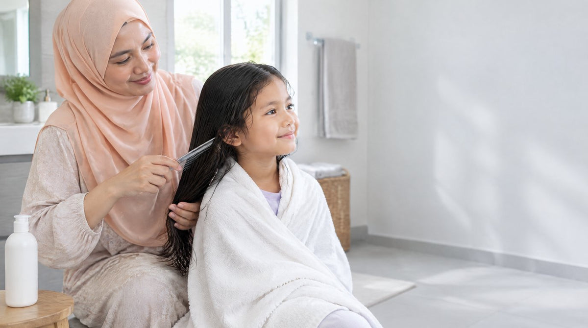 A mother combing the damp hair of her young daughter with a fine-toothed comb