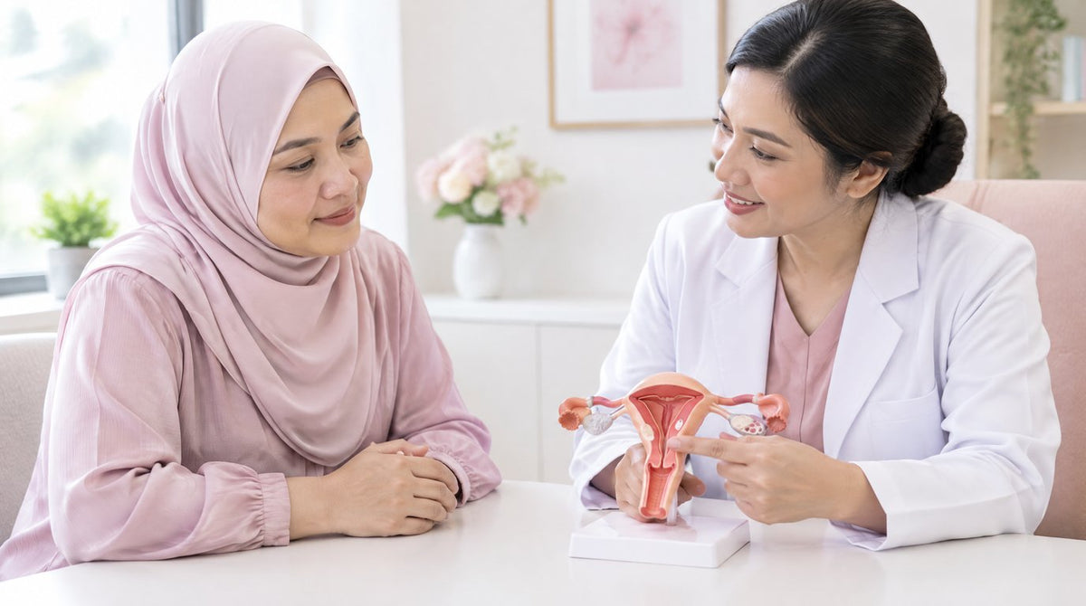 A woman in a hijab listening to a female doctor explain a model of the womb